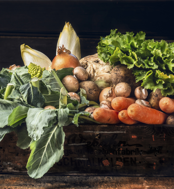 Lettuce, potatoes, onions, greens and carrots in a wooden produce box