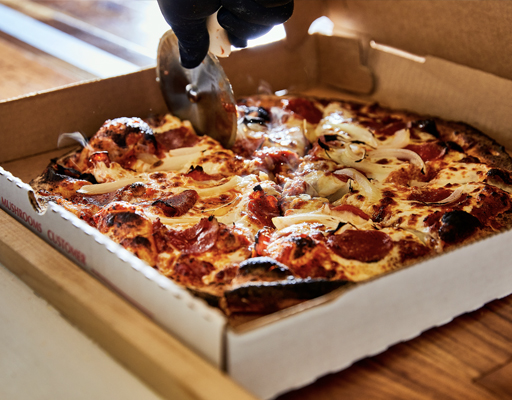 Close up of pepperoni pizza in pizza box being cut 